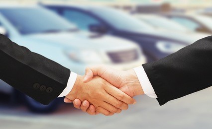 business man shake hand with rental car background
