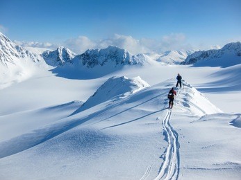 high altitude view of two skiers walking on a mountain ridge in the lyngen alps, norway