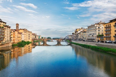 old town with bridge santa trinita reflecting in water of river arno, florence, italy