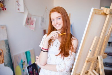 cheerful attractive young woman artist painter sketches by pencil in drawing class 