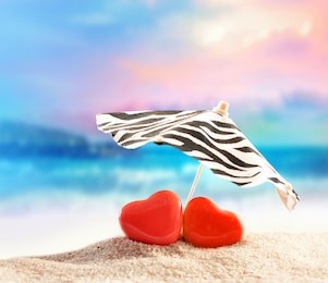 two hearts under umbrella on the summer beach. valentines day.
