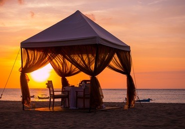 the romantic dinner setting on the beach at sunset
