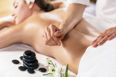 young beautiful woman enjoying massage on the table at spa center