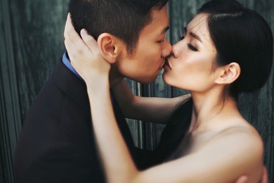 beautiful stylish asians bride and groom embracing and kissing on their wedding day on the summer streets of venice, italy