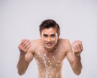 smiling man washing his face with fresh water