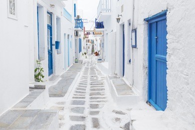 streetview of mykonos with whitewashed walls and blue doors and windows, greece