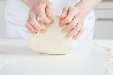 unrecognizable female cook kneading dough on the table