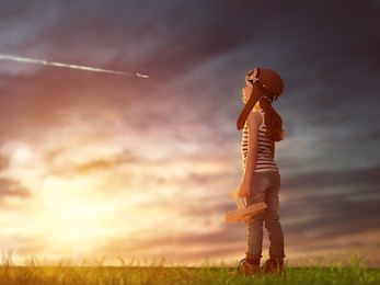 dreams of flight! child playing with toy airplane against the sky at sunset