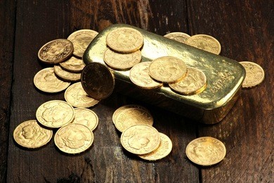 swiss vreneli gold coins and a gold ingot on wooden background