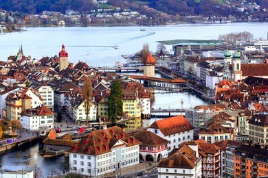 aerial view of the red tiled roofs of the old town of lucerne, wooden chapel bridge, stone water tower, reuss river and lake lucerne, switzerland
