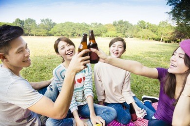 happy young friends enjoying picnic and drinking beer