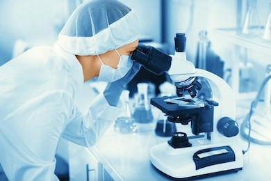 young woman medical researcher looking through microscop slide in the life science (forensics, microbiology, biochemistry, genetics, oncology) laboratory. medicine concept. 