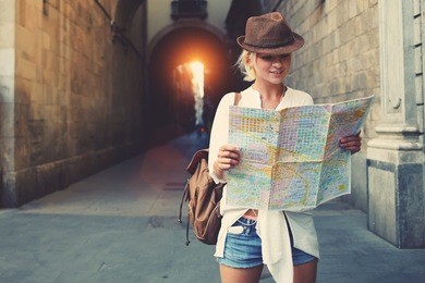 cheerful woman wanderer with trendy look searching direction on location map while traveling abroad in summer, happy female tourist searching road to hotel on atlas in a foreign city during vacation