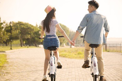 happy young couple riding on bicycle in city park