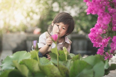 asian boy with magnifying glass outdoors,vintage filter