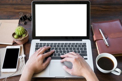 a man is working by using a laptop computer on vintage wooden table. hand typing on a keyboard. front view.