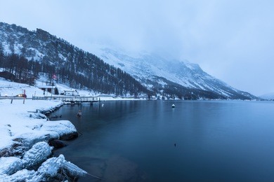 view of sils lake in winter at night fall, small village plau da lej, engadine, canton of grisons, switzerland
