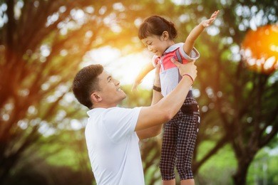 portrait of little girl hugging her daddy with nature and sunlight, family concept