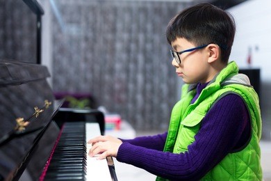 asian cute boy playing piano at home