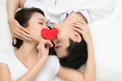 concept for valentine's day. lover couple kissing with a red heart in bed