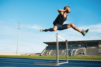 young athlete jumping over a hurdle during trai