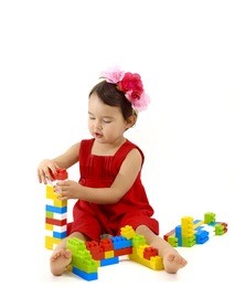 funny child girl playing with construction set over white background
