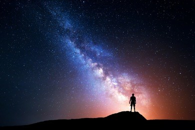 milky way. night sky with stars and silhouette of a standing happy man with yellow light. space background