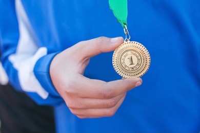 hand of the man and medal close up. the winner holds a medal. victory in competitions. first place. the hand holding a gold medal. soccer winner. 