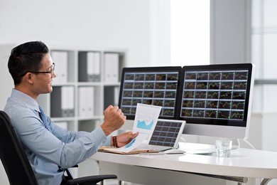 happy excited financial broker looking at the business chart in his hand