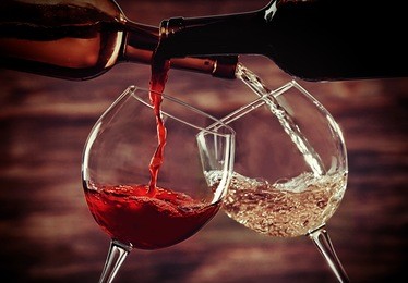 white and red wine pouring in glasses on wooden background