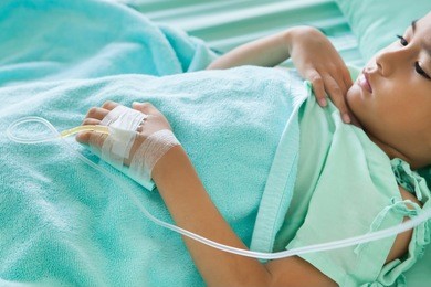 hand of the patient on the bed,little boy sick in the hospital with saline intravenous (iv),focus hand