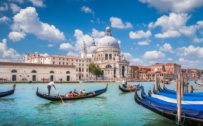 beautiful view of traditional gondolas on canal grande with historic basilica di santa maria della salute in the background on a sunny day in venice, italy
