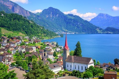 little swiss town with gothic church on lake lucerne and alps mountain, switzerland