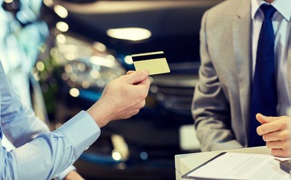 customer giving credit card to car dealer in salon