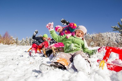 happy children sledding at winter time. group of children spending a nice time in winter.