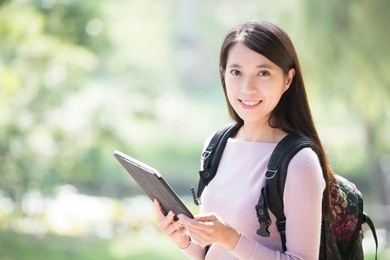 young woman student smile with digital tablet. nature green background, asian beauty