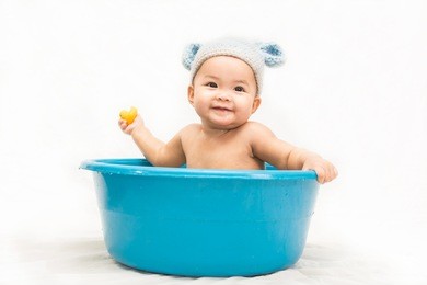 seven  month old asian baby in bathtub and she play yellow duck on white background