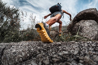 lady hiker walking through the rocky land. focus on the foot