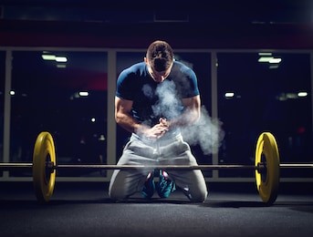 handsome weightlifter preparing for training. shallow depth of field, selective focus on hands and dust.