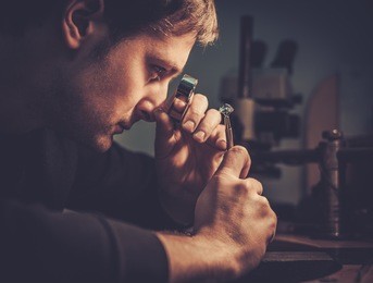 jeweler looking at the ring through microscope in a workshop.