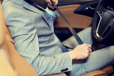 close up of man fastening seat safety belt in car