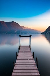 sunset at lake lugano, switzerland with wooden jetty as the foreground