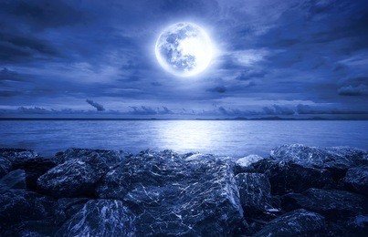 full moon over the ocean with clouds and rocks