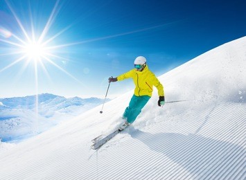 skier skiing downhill during sunny day in high mountains