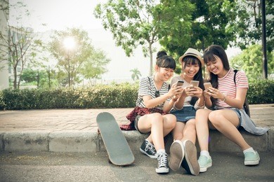 laughing girls playing on their smartphones outdoors