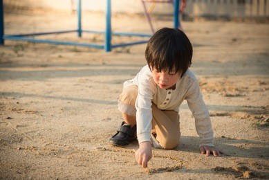asian child playing with sand in the playground