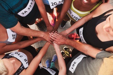 high angle portrait of a sports team standing in a circle with their hands stacked. team of runners with hands together after competition.