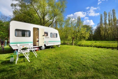 caravan trailer on a green lawn, on a sunny spring day