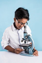 curious little indian asian school kid or scientist studying science, experimenting with chemicals or microscope at laboratory, selective focus