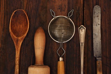 vintage kitchen utensils on rustic wood background.  closeup with low key, natural side-lighting for effect.